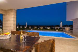 a dining table and chairs in front of a swimming pool at Villa F&A ZadarVillas in Donje Raštane