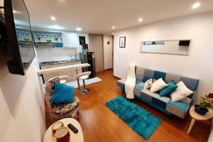 sala de estar con sofá azul y cocina en HOMY APARTAMENTOS #6 - Corferias, embassy, airport, G12, UN, Agora, en Bogotá