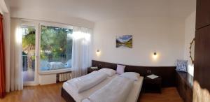 Un dormitorio con dos camas y una gran ventana. en Residence Atlantic, en Merano