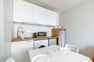 eine kleine Küche mit einem Tisch und einem Waschbecken in der Unterkunft Modern and bright flat in Monplaisir district Lyon center - Welkeys in Lyon
