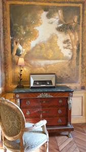 una habitación con un tocador con una pintura y una silla en La Villa des Arts, en Savigné-lʼÉvêque