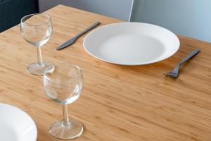 リヨンにあるModern and nice studio in Monplaisir district Lyon - Welkeysの木製テーブルの上に置かれたワイングラス2杯と白皿