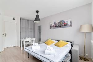 um quarto branco com uma cama com almofadas amarelas em Nice and modern studio in Monplaisir district in Lyon - Welkeys em Lyon