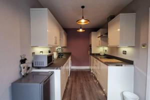 a kitchen with white cabinets and a microwave at Broomfield Cottage South Luss in Glasgow