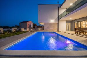 a swimming pool in the backyard of a house at night at Villa F&A ZadarVillas in Donje Raštane