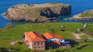 une maison avec un toit orange sur une île dans l'eau dans l'établissement Hotel Migal, à Cue