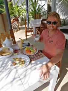 a man sitting at a table with a plate of food at Sandil Surf house in Ahangama