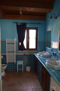 un bagno blu con due lavandini e una finestra di Villa Manu a Lapedona