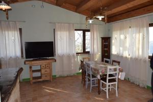 ein Wohnzimmer mit einem TV und einem Tisch mit Stühlen in der Unterkunft Villa Manu in Lapedona