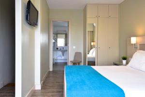 a hotel room with a bed with a blue blanket at Aqualuz Lagos by The Editory in Lagos