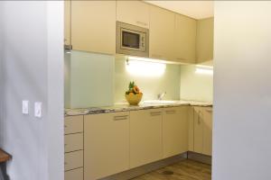 a kitchen with white cabinets and a sink and a microwave at Aqualuz Lagos by The Editory in Lagos