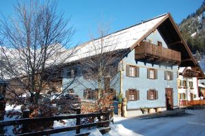 Une grande maison blanche avec un toit en bois dans la neige dans l'établissement Ferienhaus Alpenglück, à Gaicht