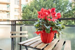 un jarrón de flores rojas sentado en un banco de madera en Torri & Portici, en Bolonia