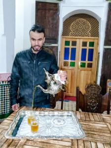 een man aan een tafel met een zilveren dierenkan bij Riad Ranya in Fès