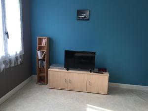una TV seduta su un supporto in una stanza con una parete blu di Chez Mimi a Châtillon-sur-Seine