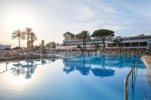 une grande piscine avec de l'eau bleue et des palmiers dans l'établissement Sol Marbella Estepona Atalaya Park, à Estepona