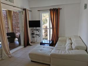 a living room with a white couch and a television at Rayon Vert Bleuphorie Beach Apartment in Flic-en-Flac