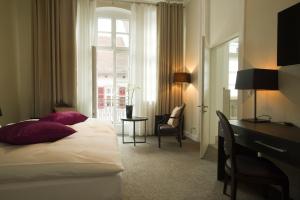 a hotel room with a bed and a desk and a window at Hotel Residenz am Königsplatz in Speyer