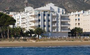 a large white building on the beach next to the ocean at Kione Las Margaritas in Alcossebre