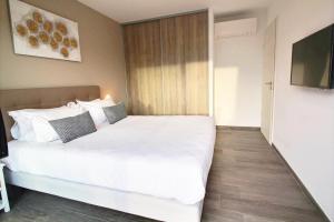 a bedroom with a white bed and a television at Residence ACQUA LINDA Porticcio in Porticcio