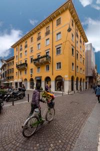 una persona montando una bicicleta frente a un edificio amarillo en Corte Melone room rental, en Verona