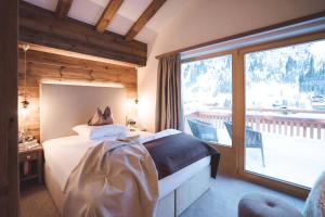 hotel & chalet madlochBlick في ليش ام ارلبرغ: غرفة نوم بها سرير ونافذة كبيرة +112 صورة