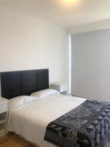 Un dormitorio con una cama con una manta blanca y negra. en Departamento de 2 ambientes luminoso en Mar del Plata