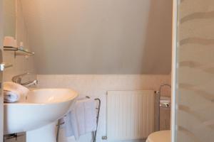 a white bathroom with a sink and a toilet at Restaurant & Chambres d'Hôtes L'Eau Vive in Fatouville-Grestain