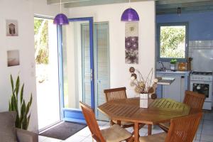 uma cozinha com uma mesa de madeira e cadeiras com luzes roxas em Maison avec jardin clos. Animaux acceptés - Wifi - Proche plages de la Trinité sur Mer et Carnac em La Trinité-sur-Mer