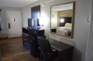 a hotel room with a bed and a desk and a mirror at Hill Country Inn in Marble Falls