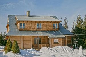 a wooden house with a metal roof in the snow at Pokoje u Uli in Kościelisko