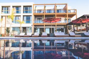 a hotel with chairs and umbrellas next to a swimming pool at Amouage by Surf Maroc in Taghazout