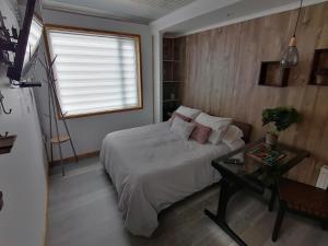 a bedroom with a bed and a table and a window at Espacio Innata in Punta Arenas