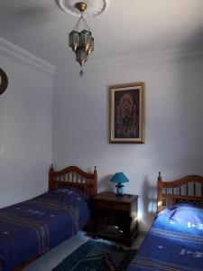 a bedroom with two beds and a table with a lamp at Dar El Goulli in Hammam Sousse
