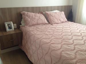 ein Bett mit einer rosa Bettdecke und Kissen darauf in der Unterkunft 2 Quartos com Piscina Aquecida Melhor Bairro Brasília in Brasilia + 27 Fotos