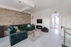 a living room with a green couch and a stone wall at ANITAHOUSE in Vila Nova de Gaia