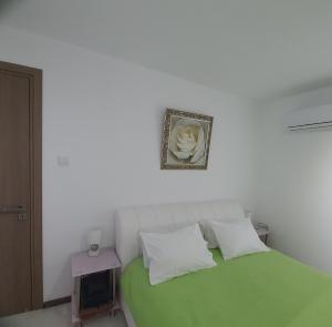a bedroom with a green bed with a picture on the wall at Luxury 2 bed Apartment next to the Beach in Paralimni