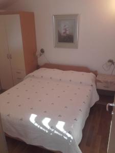 een bed met een wit dekbed in een slaapkamer bij Apartman-NENA- in Veli Iž