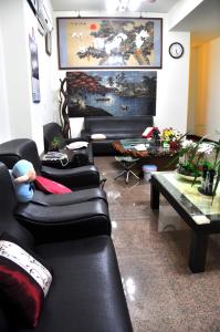 sala de estar con sofás de cuero negro y mesa en Fish Fun House en Hualien