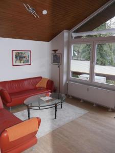 ein Wohnzimmer mit einem roten Sofa und einem Glastisch in der Unterkunft Ferienwohnung Haus Sonnenberg in Bremervörde