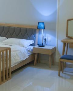 a bedroom with a bed with a blue lamp on a table at شاليهات فيفيان بارك Vivian Park Chalets in Al Kharj