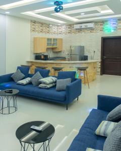 ein Wohnzimmer mit blauen Sofas und eine Küche in der Unterkunft شاليهات فيفيان بارك Vivian Park Chalets in Al Kharj