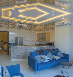 a living room with blue couches and a kitchen at Vivian Park Chalets in Al Kharj
