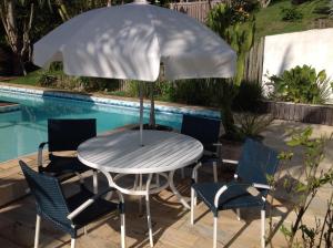 a table and chairs with an umbrella next to a pool at Deauville Pousada in Búzios