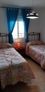 a bedroom with two beds with blue curtains and a window at Apartamento Naturaleza Virgen in Matalascañas