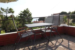 un tavolo e 2 sedie seduti su un balcone di Apartments Rakovic a Lovran (Laurana)