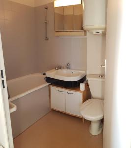 een badkamer met een wastafel, een toilet en een bad bij Bord de plage, thalasso et vue mer ! in Cabourg