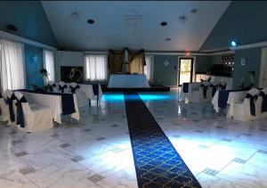 una sala de banquetes con mesas y sillas blancas en una habitación en Araamda Inn, en Norcross