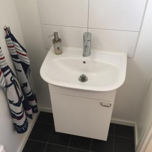La salle de bains est pourvue d'un lavabo blanc et d'une douche. dans l'établissement Peaceful Cottage, à Göteborg
