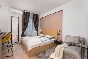 ein Schlafzimmer mit einem Bett, einem Tisch und einem Stuhl in der Unterkunft Deluxe Apartments & Rooms "In the Center" in Rijeka